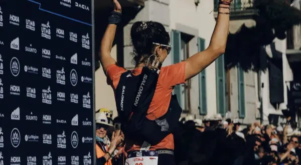 Coureuse célébrant sa victoire à l'UTMB, portant son sac d'hydratation et le matériel obligatoire.
