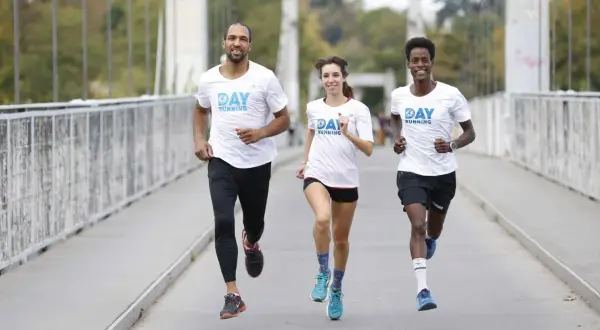 Trois coureurs souriants sur un pont, profitant des bienfaits de la course à pied.