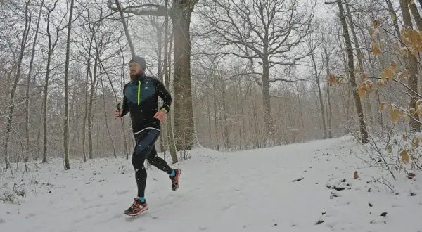 Un coureur s'entraîne sur un sentier enneigé, profitant d'une course hivernale près de Saint-Étienne, Lyon.
