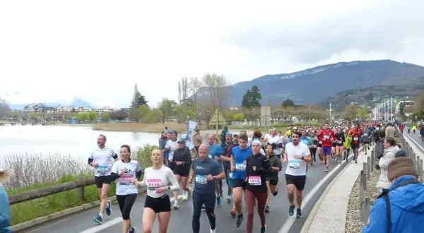 Course à Aix-les-Bains : une foule de coureurs participe à un marathon au bord du lac, avec des montagnes en toile de fond.