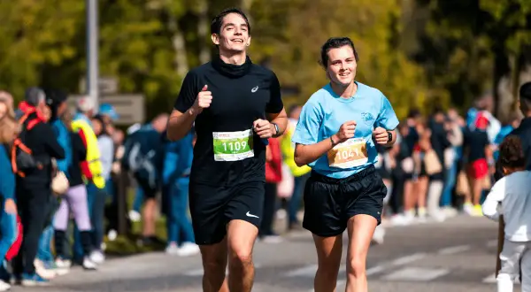 Deux coureurs souriants participent au semi marathon de Madrid, le numéro 1109 et le 1041.