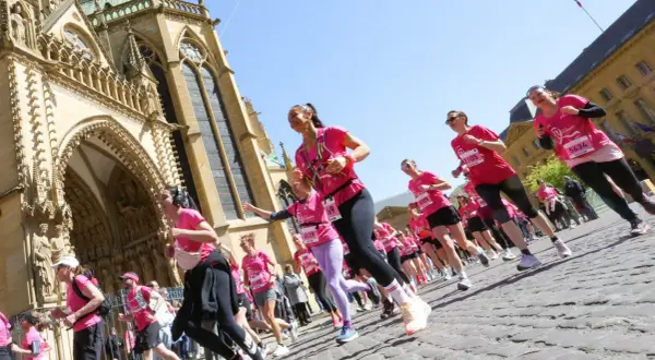 Course de femmes en rose lors du semi-marathon de Tulle, devant une cathédrale majestueuse.