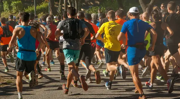 Un groupe de coureurs s'élance sur un chemin, certains portent un gilet lesté pour un entraînement plus intense.