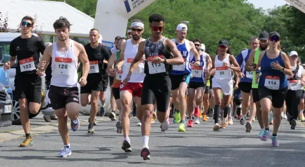 Course à pied en Île-de-France, des coureurs franchissent une arche de départ. L'un d'eux porte le dossard 113.