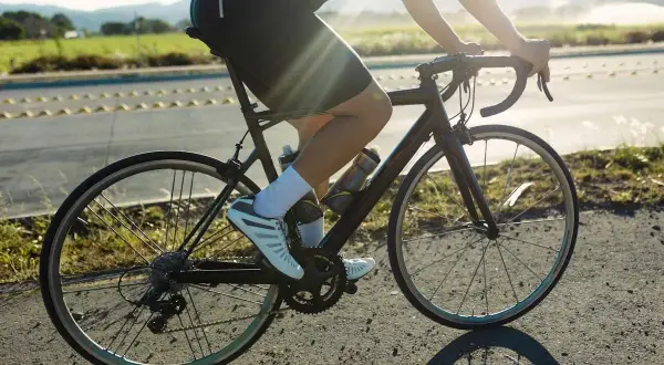 Cycliste en pleine action, profitant d'une belle journée pour le vélo et la course à pied. Le soleil brille sur la route.