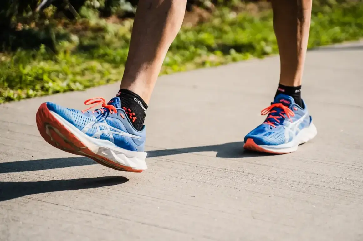 Course à pied avec des chaussures bleues et oranges. Le pied gauche montre une légère pronation, typique d'une foulée naturelle.