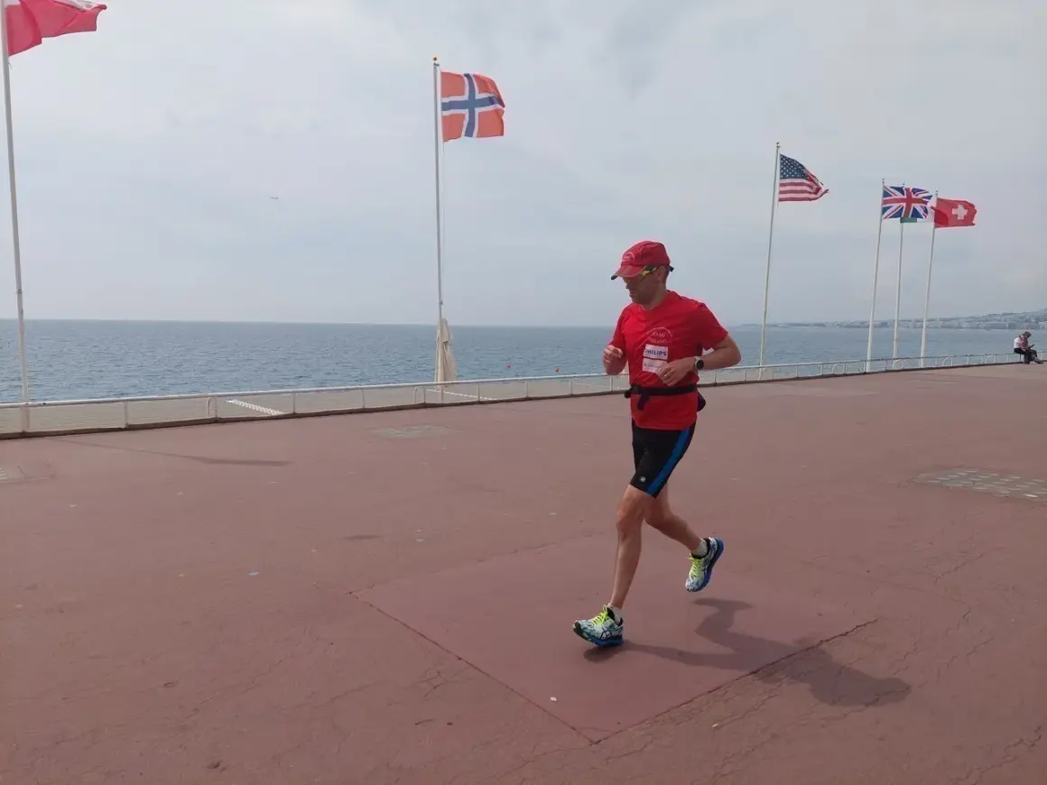 Un homme court sur la promenade des Anglais à Nice, drapeau norvégien et américain en arrière-plan.