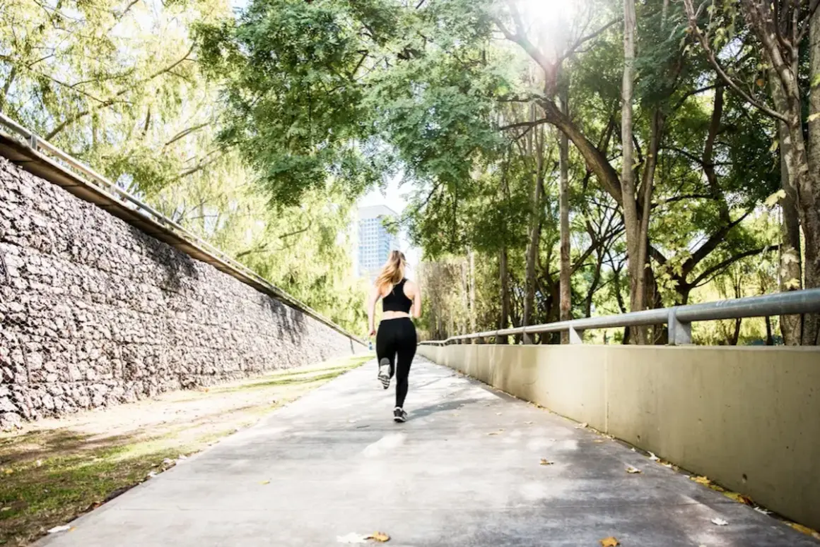 Une femme court sur un chemin ensoleillé, s'entraînant pour le semi marathon Venise.