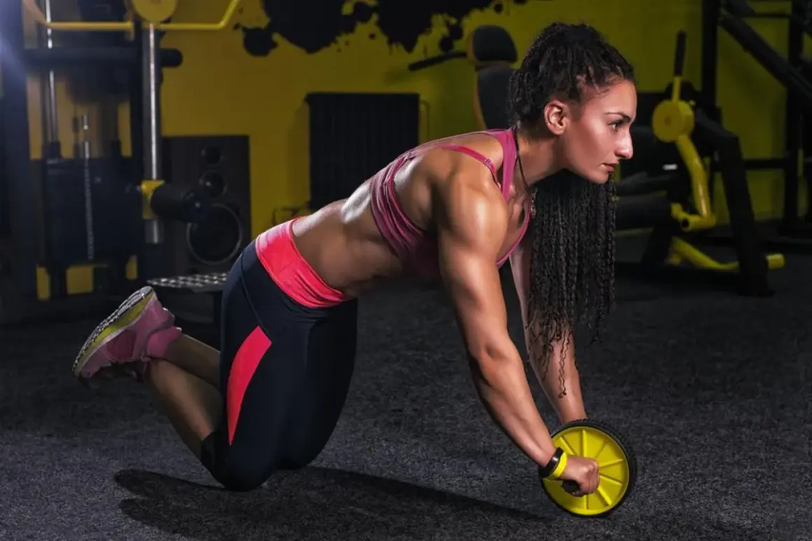 Femme musclée en plein **exercice roue abdominale** dans une salle de sport.
