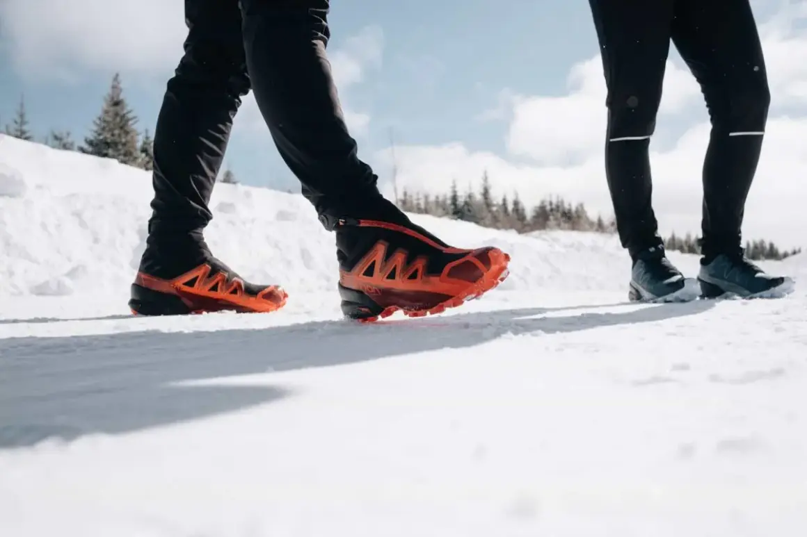 Deux personnes en chaussures de trail, l'une avec des chaussures orange vif, parcourent un sentier enneigé du Haut Giffre.