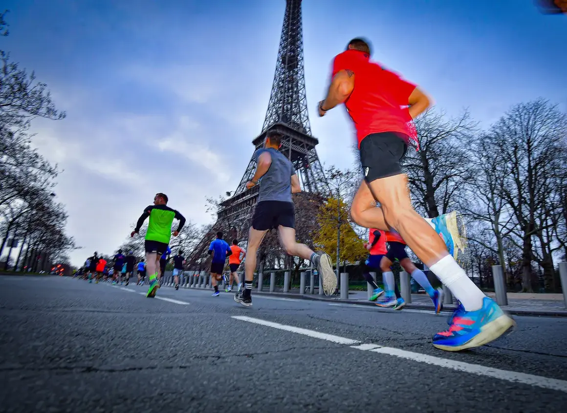 Course de 10 km tour Eiffel, des coureurs en tenue de sport dévalent la route, le monument parisien en arrière-plan.