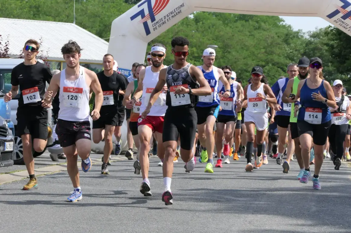 Course à pied en Île-de-France, des coureurs franchissent une arche de départ. L'un d'eux porte le dossard 113.