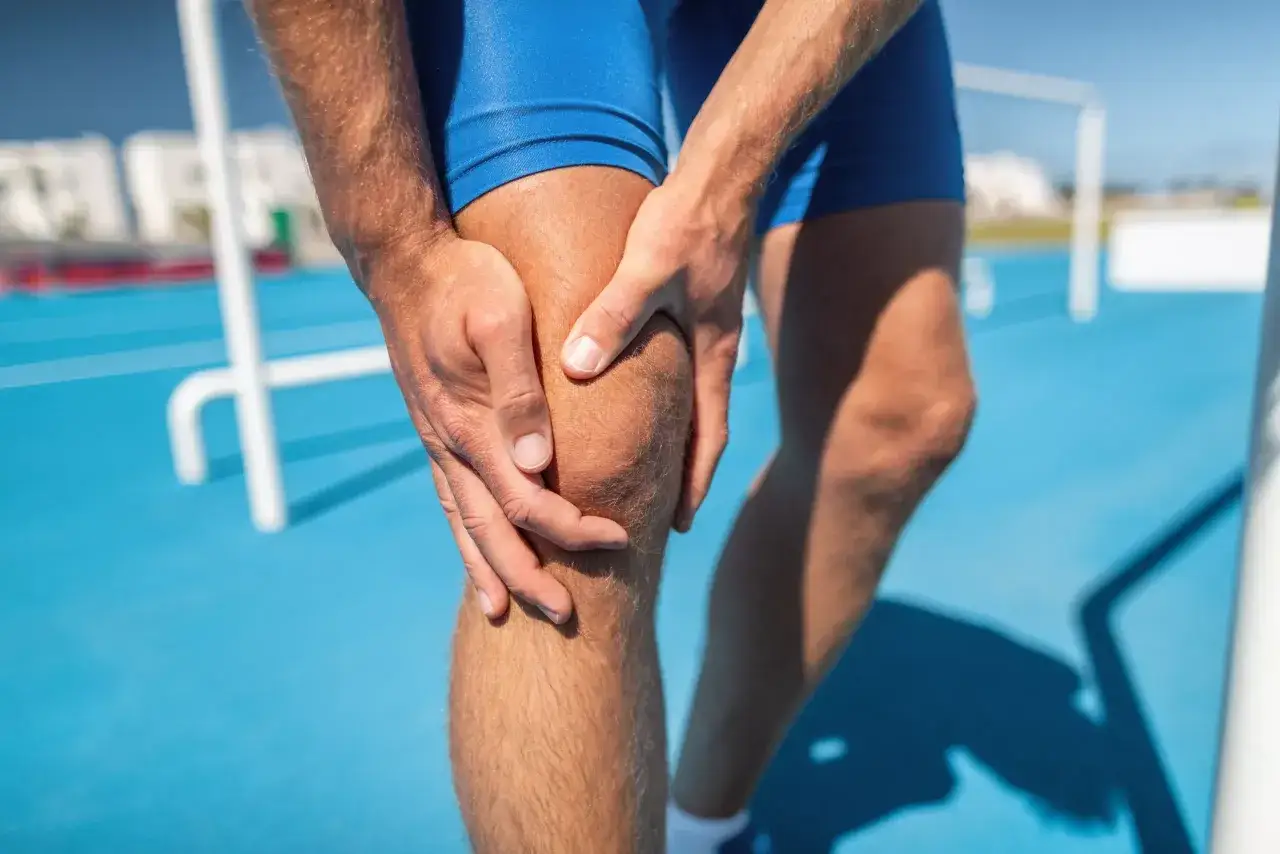 Athlète tenant son genou, souffrant d'une douleur qui pourrait indiquer un temps de guérison fracture de fatigue.