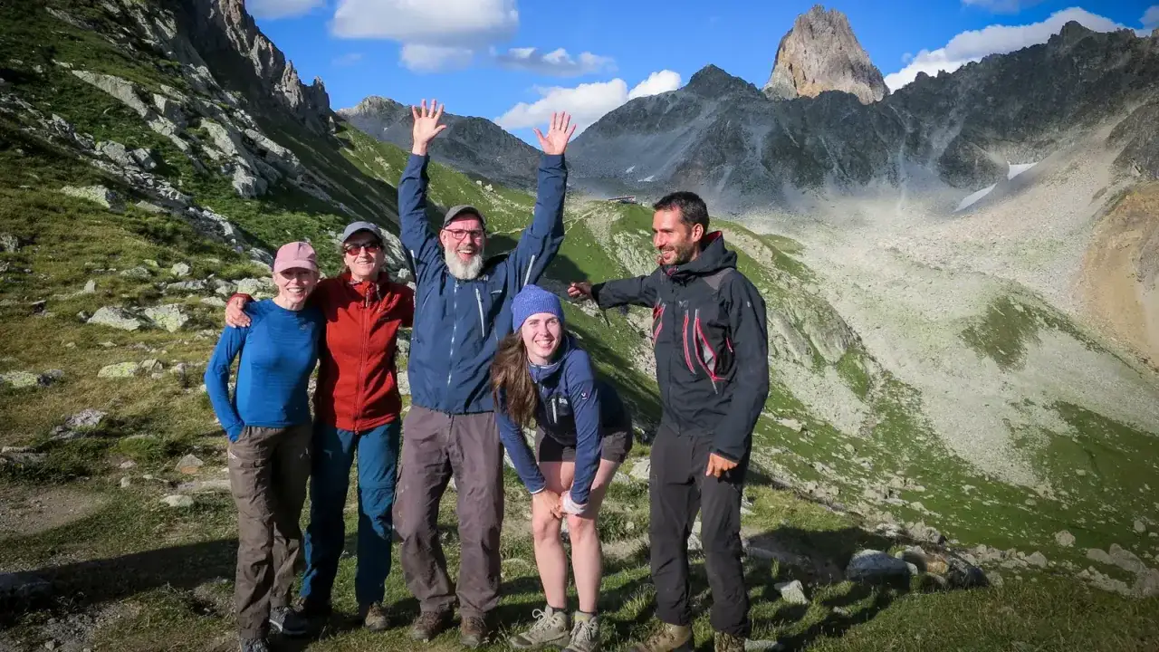 Cinq randonneurs souriants, l'ultra spirit dans les montagnes. Le soleil brille sur les sommets escarp&eacute;s.