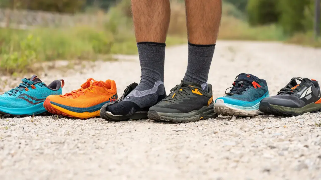 Une s&eacute;lection de chaussures de trail running color&eacute;es align&eacute;es sur un chemin de gravier, pr&ecirc;tes pour une aventure sur le road run trail.