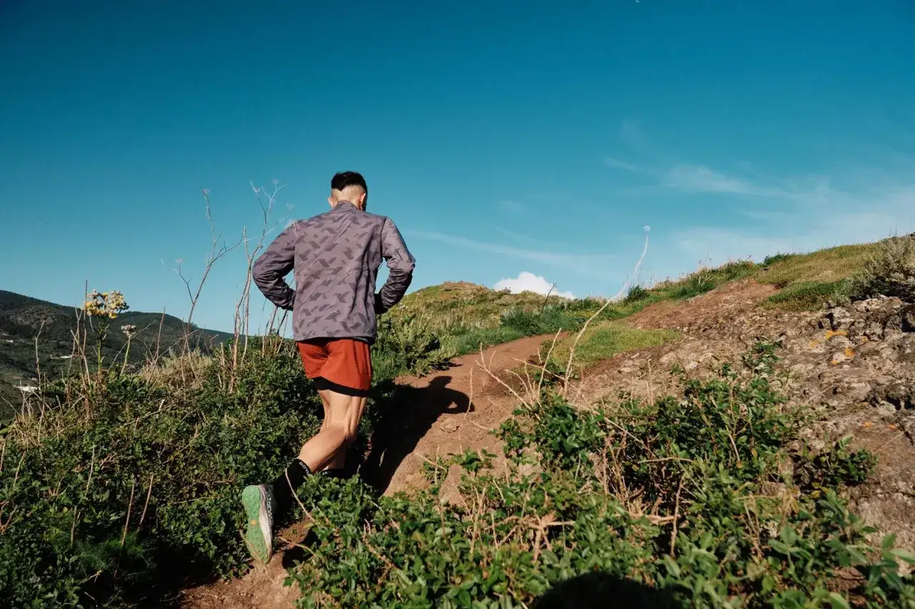 Un homme court sur un sentier rocailleux sous un ciel bleu &eacute;clatant. Il aime courir tous les jours pour profiter de la nature.