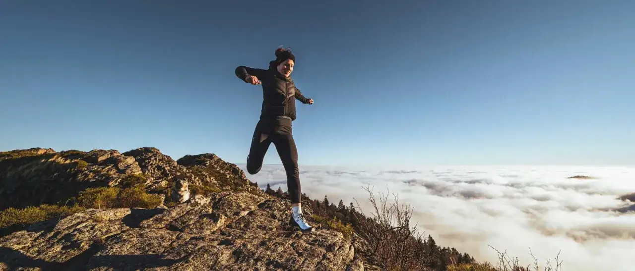 Une coureuse saute au-dessus des nuages, un paysage de trail actualit&eacute; &agrave; couper le souffle.