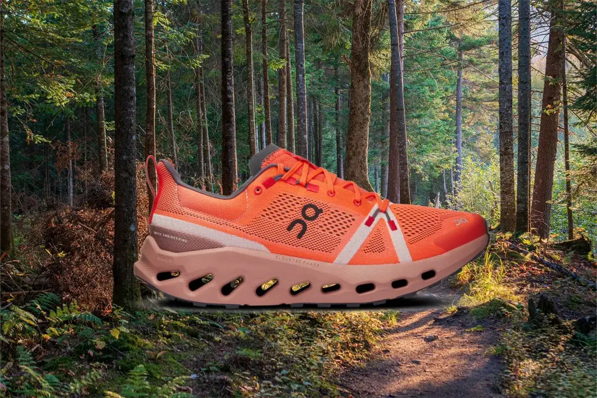 Chaussure de trail orange vif, prête à vous aider à commencer la course à pied sur ce sentier forestier ensoleillé.