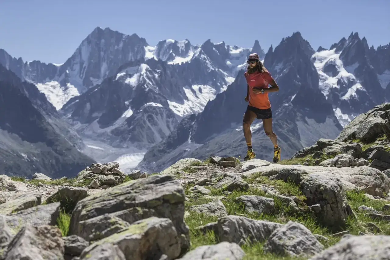 Un coureur en plein effort sur le trail du Haut Giffre, avec des montagnes enneigées en arrière-plan.