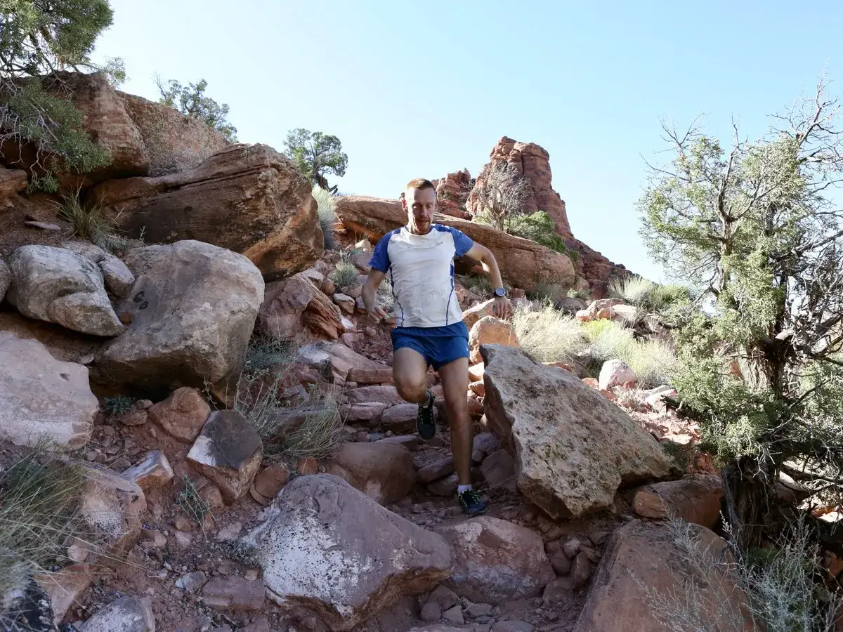 Un coureur dévale un sentier rocheux, visiblement né pour courir dans ce paysage désertique spectaculaire.