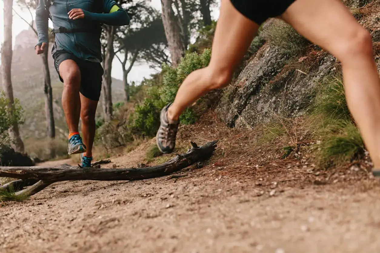 Deux coureurs s'entra&icirc;nent sur un sentier de montagne. Leurs jambes muscl&eacute;es montrent les meilleurs exercices pour les jambes en action.
