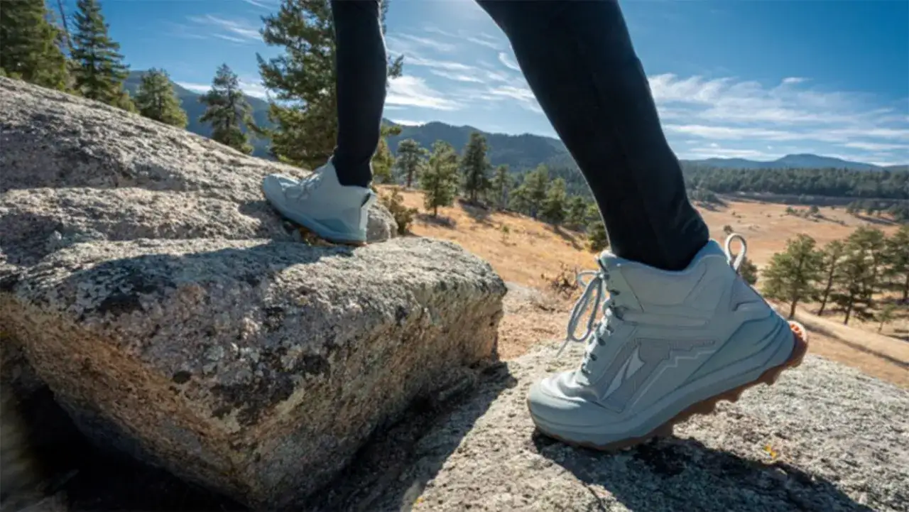 Des chaussures de trail sportif grises sur des rochers, avec un paysage montagneux en arrière-plan. Le meilleur trail sportif pour l'aventure.