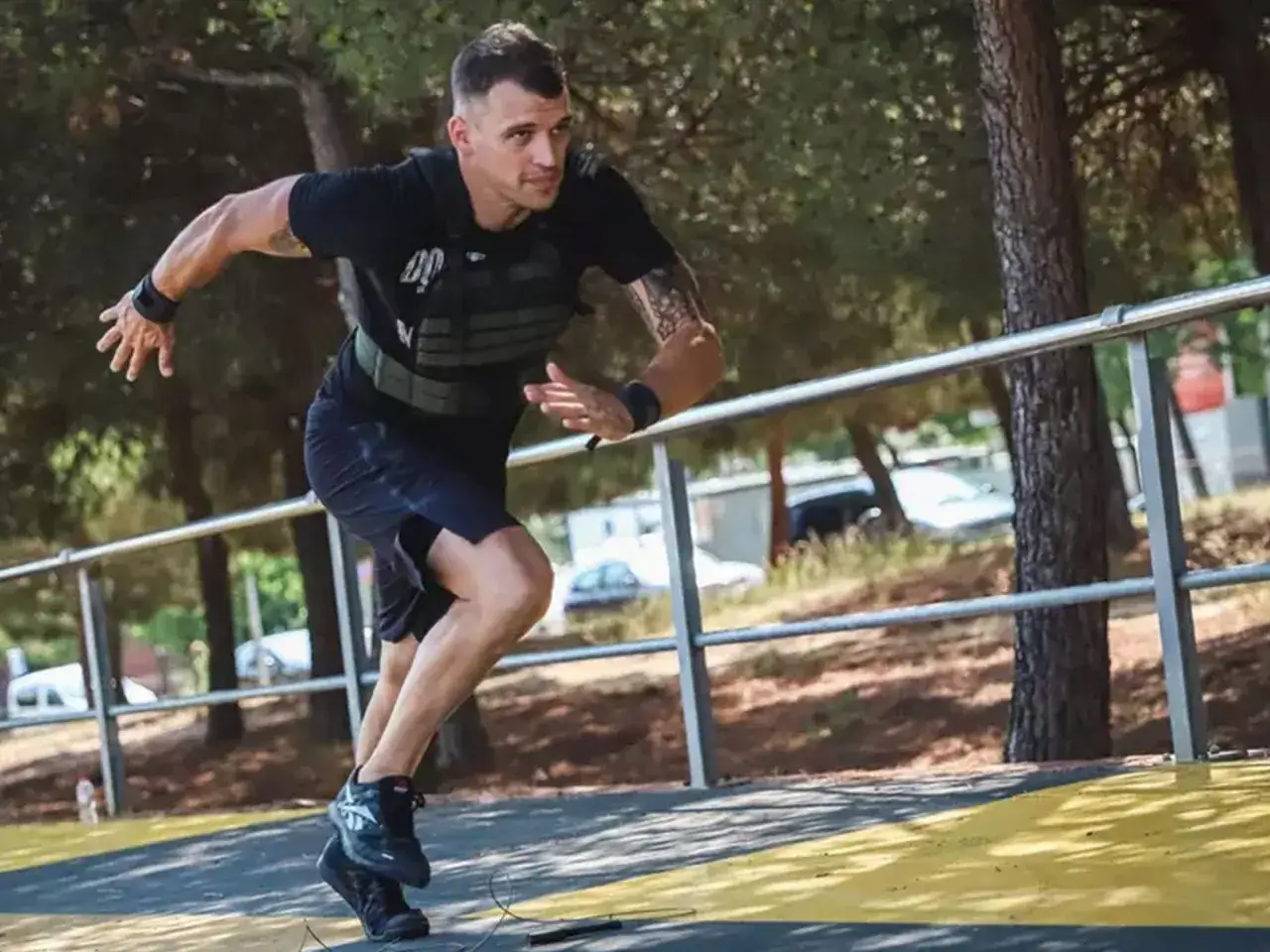 Un homme court avec un gilet lest&eacute;, s'entra&icirc;nant en ext&eacute;rieur. Ses muscles sont tendus, il est concentr&eacute; sur son effort.