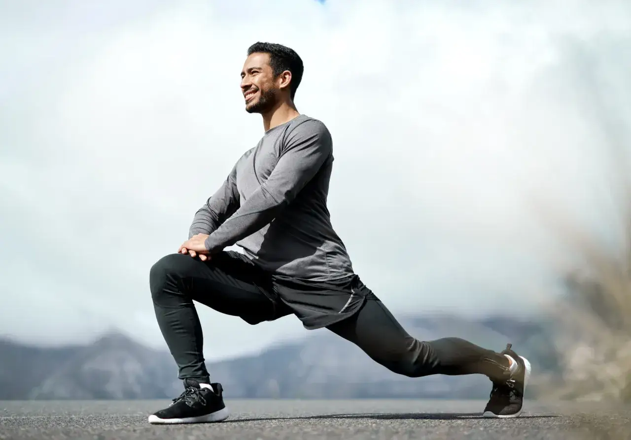 Un homme souriant s'étire en plein air, prêt pour sa séance de ppg sport.