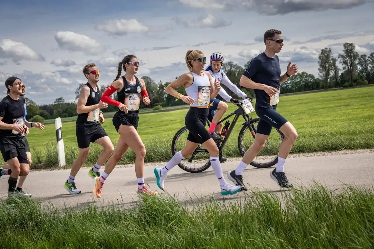Coureurs en pleine course, certains visent un programme 10km 40min. Un cycliste les accompagne.