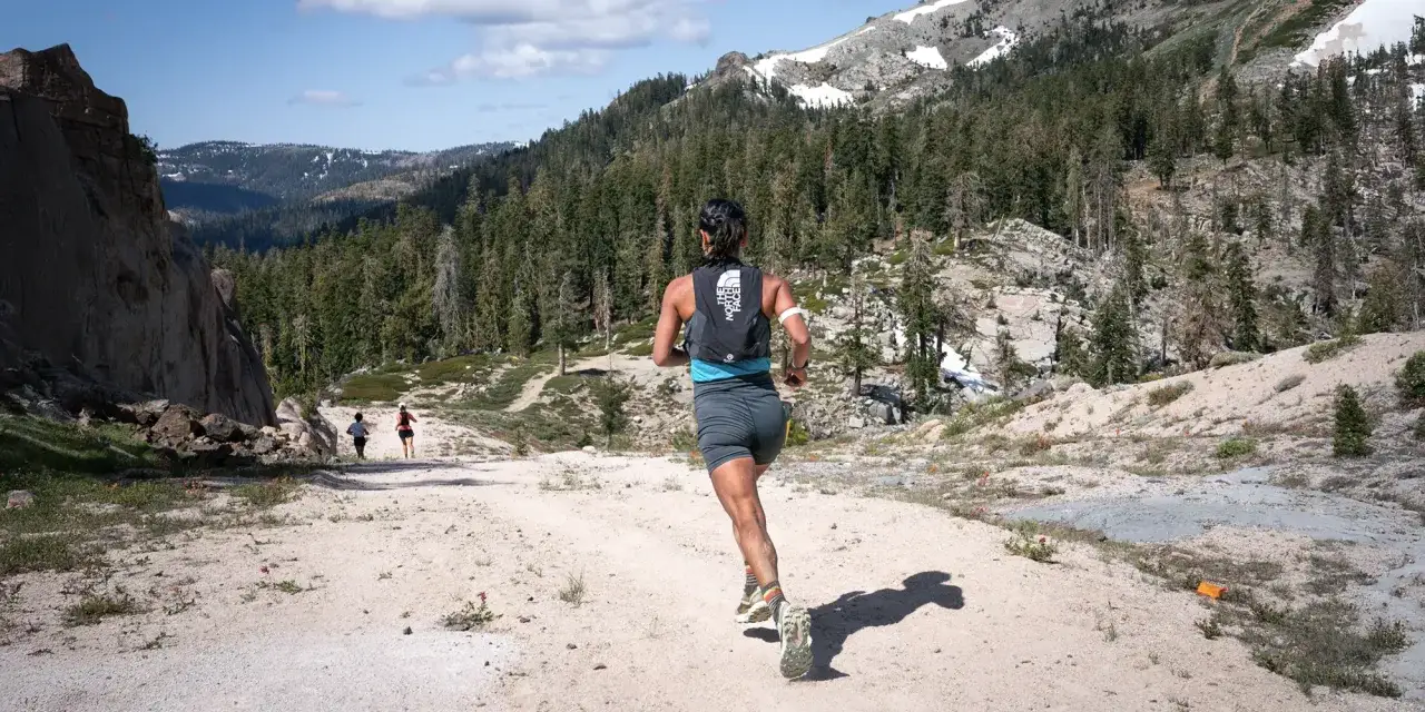 Course de trail en montagne, une femme court sur un sentier rocailleux. La pr&eacute;paration physique est essentielle pour affronter ce terrain exigeant.