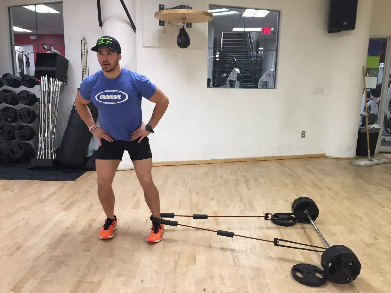 Un homme fait un exercice adducteur avec des bandes élastiques attachées à une barre chargée de poids.