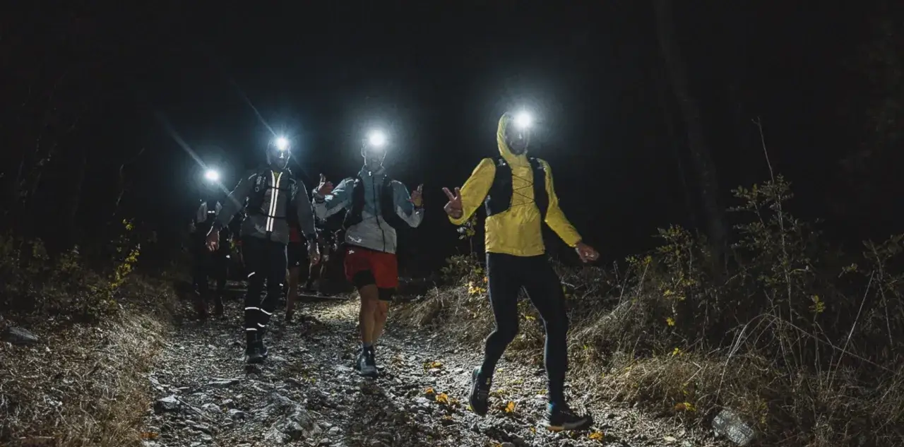 Des coureurs s'élancent dans l'obscurité, leurs lampes frontales éclairant le sentier rocailleux. Une course de nuit palpitante dans la nature sauvage.