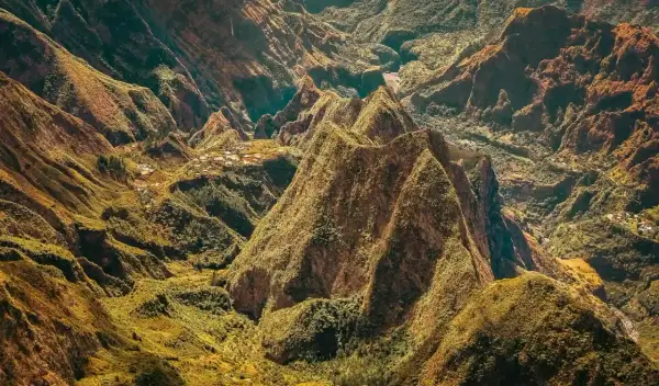 Paysage spectaculaire de montagnes verdoyantes et escarpées, rappelant les défis de la diagonale des fous. Des villages sont nichés dans les vallées.