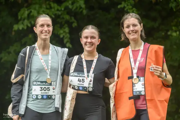 Trois coureuses souriantes, médailles au cou, célèbrent leur participation à la course RUN for PLANET.