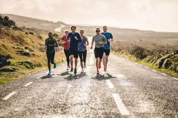 Groupe de coureurs sur une route de campagne ensoleillée. Ils s'entraînent pour comment progresser en course à pied.