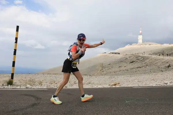 Une coureuse exulte sur la route du semi marathon du Mont Ventoux, le sommet et sa tour en arrière-plan.