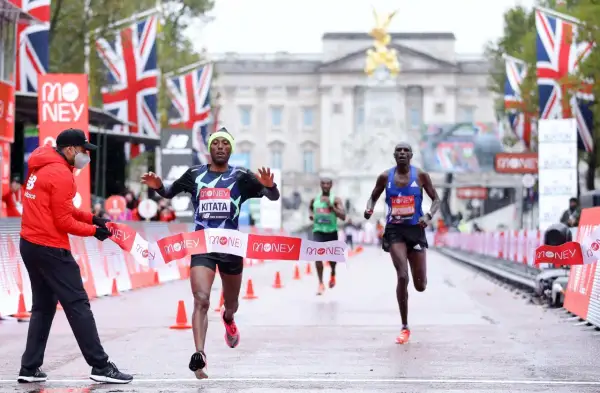 Le coureur Kitata franchit la ligne d'arrivée du marathon de Londres, sous les drapeaux britanniques.