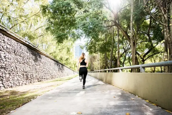 Une femme court sur un chemin ensoleillé, s'entraînant pour le semi marathon Venise.