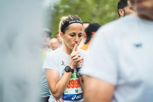 Une coureuse concentrée, mains jointes devant son visage, en pleine préparation mentale marathon.