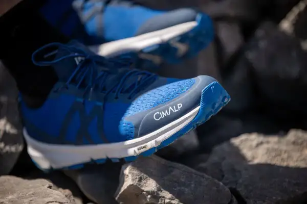 Chaussures de trail bleues CIMALP sur des rochers, parfaites pour le meilleur trail sportif.