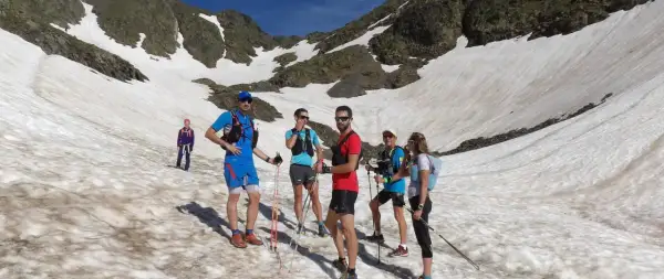 Une équipe de trail sur un sentier enneigé en montagne, profitant d'une journée ensoleillée.