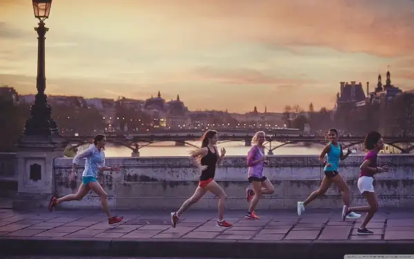 Cinq femmes courent sur un pont à Paris au coucher du soleil, profitant d'une belle soirée pour courir à Paris.