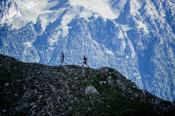 Deux coureurs s'élancent sur le **trail des Fiz**, dominant un paysage montagneux spectaculaire.