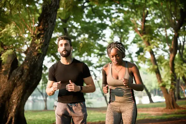 Un homme et une femme courent dans un parc, s'entraînant pour le marathon d'Annecy et son dénivelé.