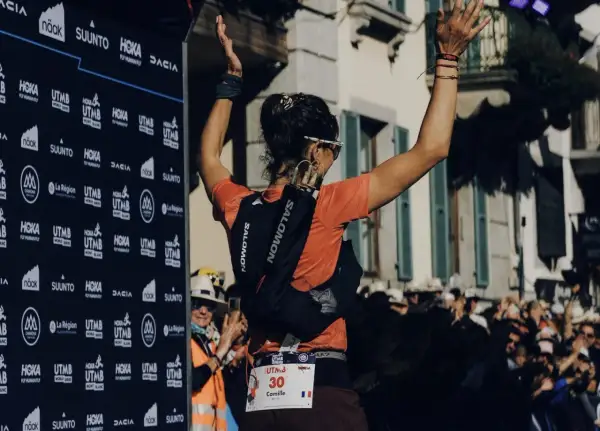 Coureuse célébrant sa victoire à l'UTMB, portant son sac d'hydratation et le matériel obligatoire.