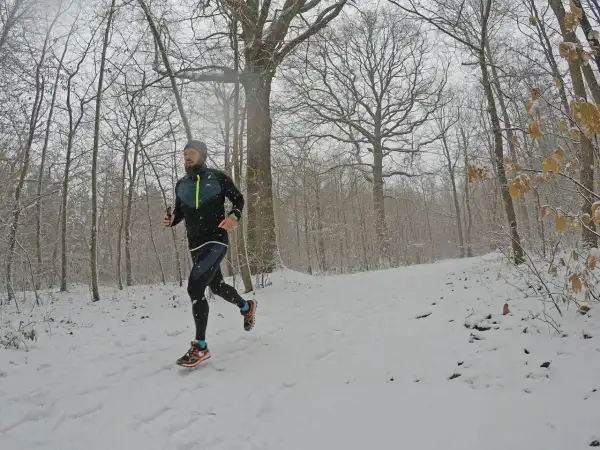 Un coureur s'entraîne sur un sentier enneigé, profitant d'une course hivernale près de Saint-Étienne, Lyon.