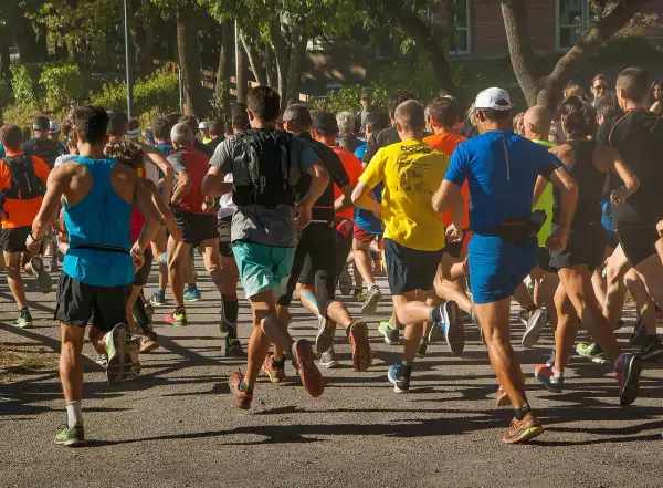 Un groupe de coureurs s'élance sur un chemin, certains portent un gilet lesté pour un entraînement plus intense.